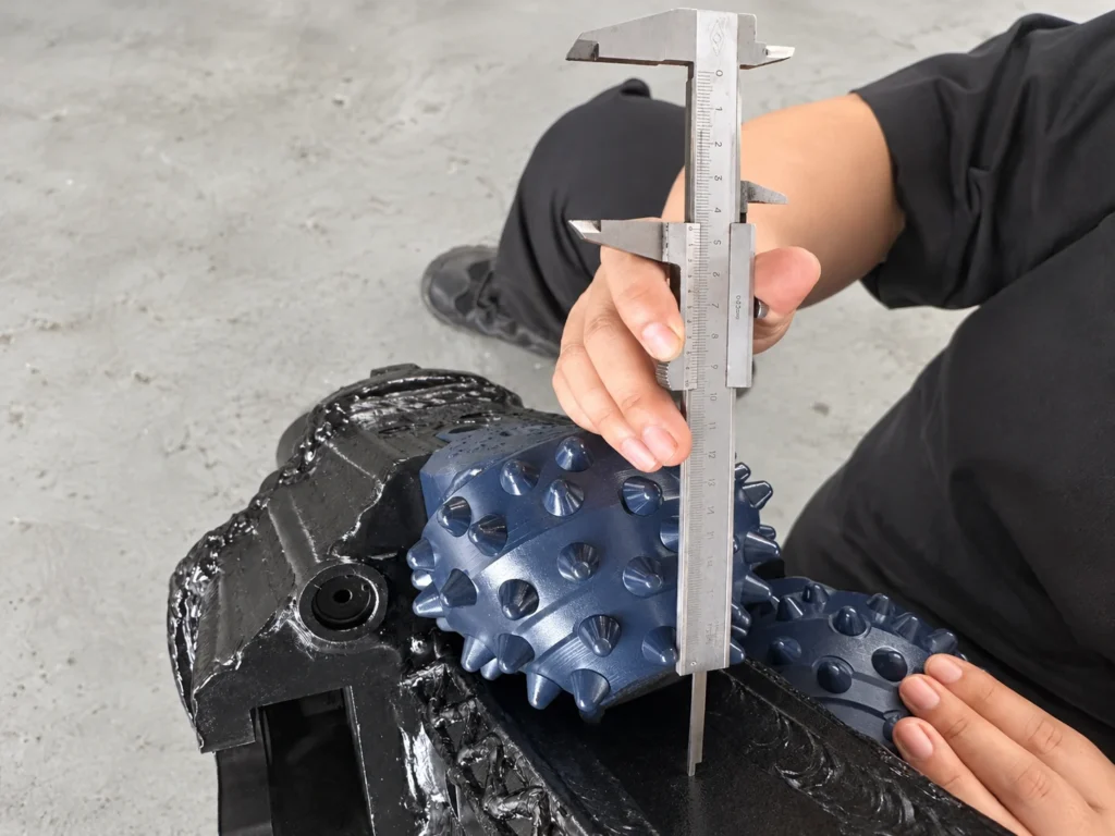 Technician measuring a Fixed Type Hole Opener roller cone cutter with a vernier caliper