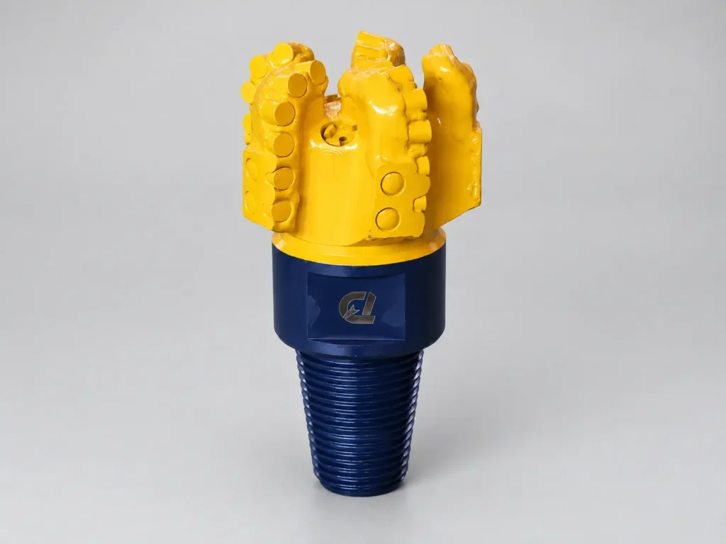 Image alt text: Yellow and blue PDC drill bit with fixed cutters for HDD pilot-hole drilling