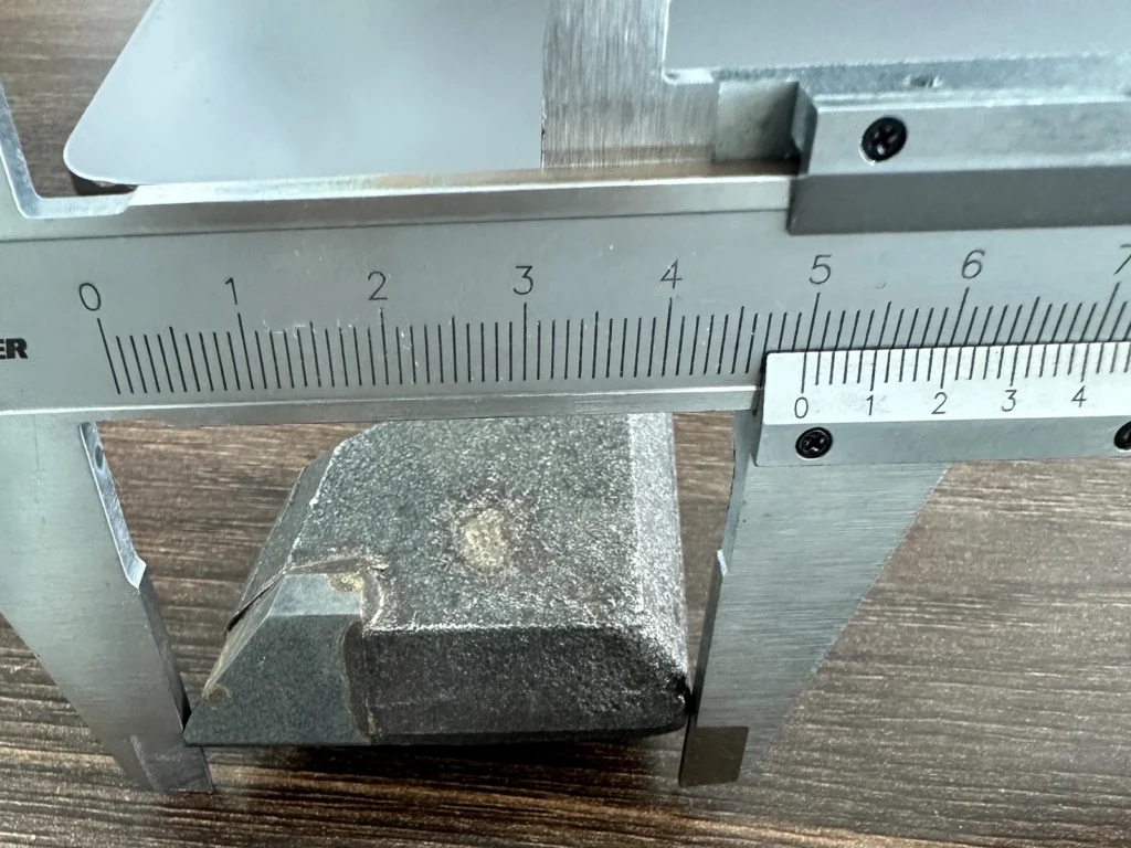 Vernier caliper measuring the width of a forged weld-on tooth during quality inspection